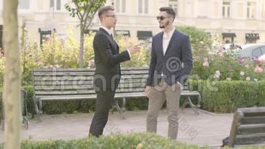 两个年轻的商人在公园里见面握手。 自信的经理在户外会见他的客户。 商务